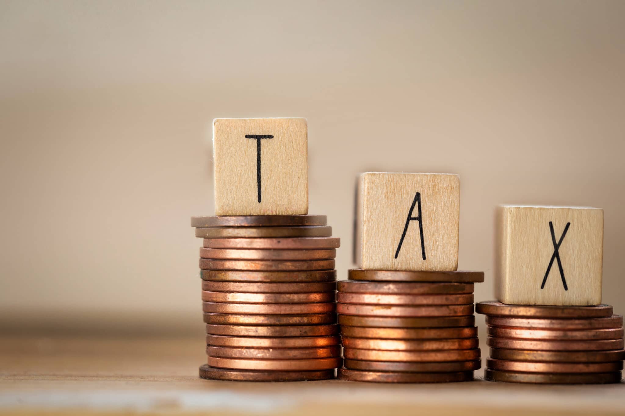 Wooden cubes with the word Tax on money climbing staits, pile of coins ,Tax Concept background closeup